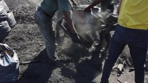 ผู้ชายในเสื้อผ้าสกปรกขยี้ผ่านบันทึกการเผาไหม้ฟืนบรรจุถ่านหินเป็นกระสอบ — วีดีโอสต็อก