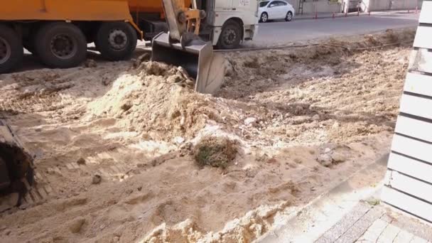 Road repair work. excavator metal bucket digs ground before laying asphalt. — Stock Video