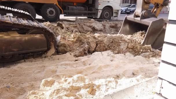 Road repair work. excavator metal bucket digs ground before laying asphalt. — Stock Video