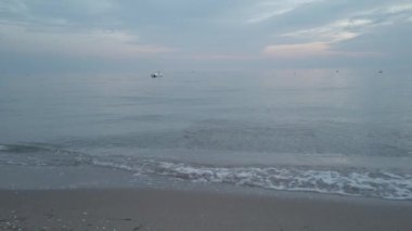 Bulutlu gökyüzü, kara bulutlar. İyi akşamlar. Gün batımı. Kumsalda. Beyaz köpüklü deniz dalgaları