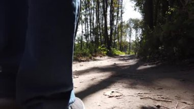 Ormanda yürüyen orta yaşlı bir adam. Günlük kıyafetli bir adam orman yolunda yürüyor.