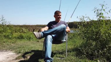 Sakallı orta yaşlı bir adam. Adam turist koltuğuna oturur, sigara içer, dinlenir..