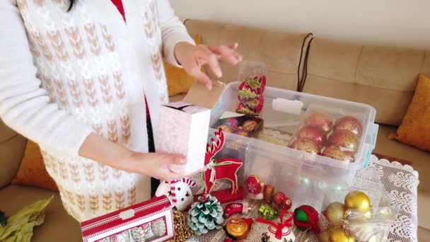 Brünette Frau holt Weihnachtsspielzeug, Kugeln aus Plastikbehälter. — Stockvideo