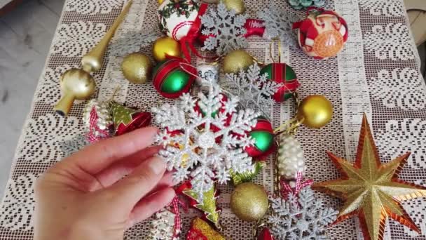 Üveg, műanyag, karácsonyfa dekoráció fehér asztalterítőn. Női kezek — Stock videók