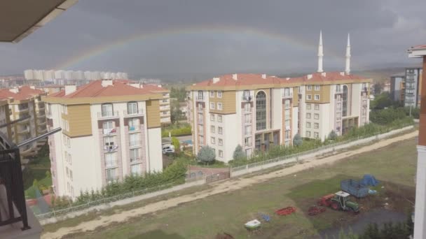 Dunkle Wolken am Himmel. Hohe Gebäude in der Ferne. Großer heller Regenbogen am Himmel — Stockvideo