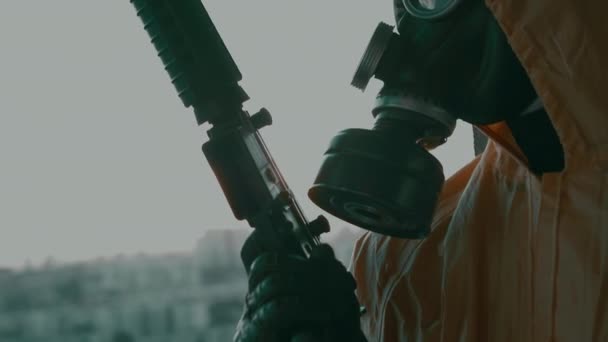 A man in a gas mask, a protective suit, with a weapon in his hand close-up. — Stock Video