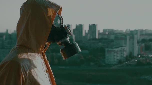 Man met gasmasker, beschermend pak met wapen kijkt naar de stad, richt zich op. — Stockvideo