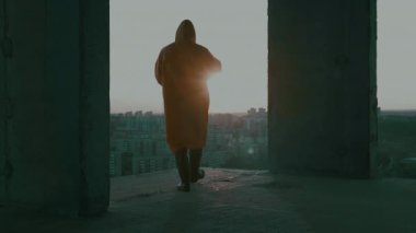 Koruyucu giysili bir adam, gaz maskeli, tamamlanmamış bir binada silahlı..