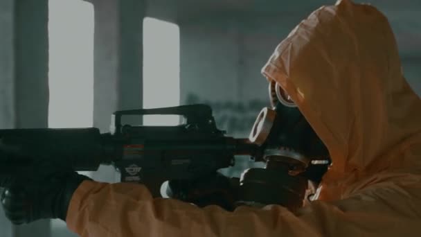Man in protective suit, gas mask, with weapon walks looks around, takes aim. — Stock Video