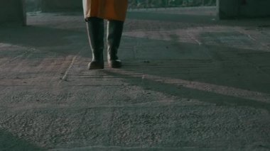 Koruyucu giysili, gaz maskeli, silahlı bir adam bitmemiş bir ofiste yürüyor.