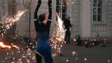 Büyük maytaplarla dönen kız oyuncu gösterisi. Altın kıvılcım kıvılcımlar.