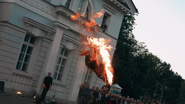 Man in jumpers makes a somersault over his head with a fiery torch in his hand. — Stock Video