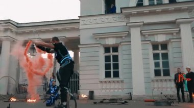 Kazaklı bir adam elinde sis bombasıyla kafasının üzerinden atlıyor..