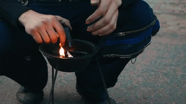 El hombre se agacha y enciende un fuego en el cuenco antes de que comience el espectáculo de fuego. — Vídeo de stock