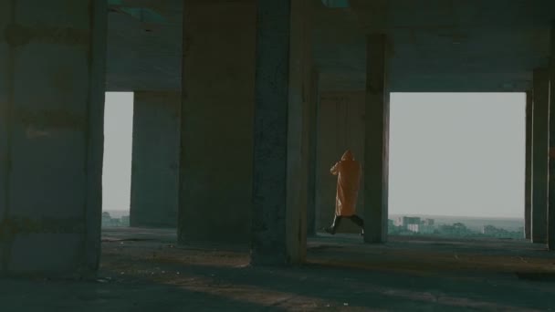 Man in beschermend pak, gasmasker, met wapen, loopt door onafgewerkt gebouw — Stockvideo