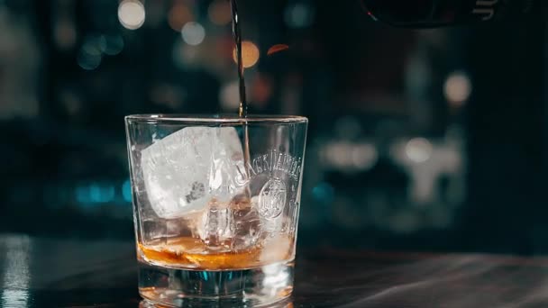 Whisky scump și rafinat dintr-o sticlă este turnat într-un pahar de gheață . — Videoclip de stoc