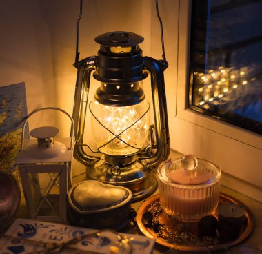 Sıcak bir akşam, evde klasik lamba, mücevher kutusu ve fener var.