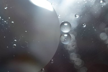 Suyun içinde renkli yağ damlaları olan soyut bir arka plan. Psikedelik desen görüntüsü. Arka planda bulanık küreler. Sudaki yağ damlaları ve gölgeler.