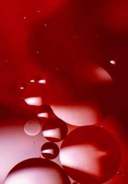 Suyun içinde renkli yağ damlaları olan soyut bir arka plan. Psikedelik desen görüntüsü. Kırmızı, mor ve kırmızı arkaplandaki küreler. Sudaki yağ damlaları ve gölgeler.