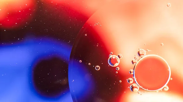 Abstract background with colorful oil drops in water. Psychedelic pattern image. Spheres on blurred red, purple and blue colored background. Oil drops and shaddows in a water.