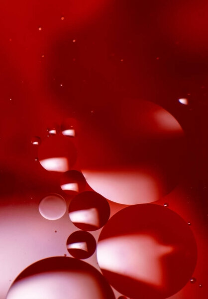 Abstract background with colorful oil drops in water. Psychedelic pattern image. Spheres on blurred red, purple and scarlet colored background. Oil drops and shaddows in a water.