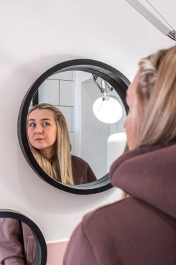 Genç bir kadın aynaya gülümsüyor. Yansıma konsepti.