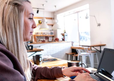 Rahat eşofmanlı genç bir kadın bilgisayarda çalışıyor. İş kadını sosyal mesafeyi koruyor ve uzaktan çalışıyor. Yeni normal kavram
