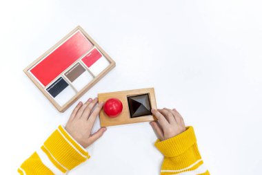 Kızların elinin en üst görüntüsü, Montessori okulundaki renkli ahşap geometrik şekiller bulmacasını çözmek ve oynamaktır. Öğrenme kaynaklarını çocuk eğitim dili ve yazımı için kullanma kavramı.