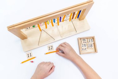 Kızların elinin en üst görüntüsü, Montessori okulundaki renkli ahşap geometrik şekiller bulmacasını çözmek ve oynamaktır. Matematiksel geometri kullanma kavramı çocuk eğitimi için kaynak öğrenme kavramı.