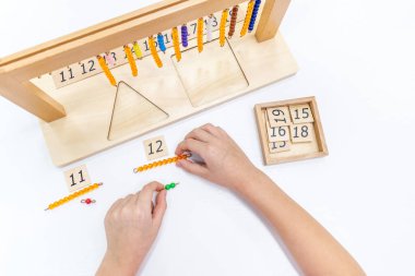 Kızların elinin en üst görüntüsü, Montessori okulundaki renkli ahşap geometrik şekiller bulmacasını çözmek ve oynamaktır. Matematiksel geometri kullanma kavramı çocuk eğitimi için kaynak öğrenme kavramı.