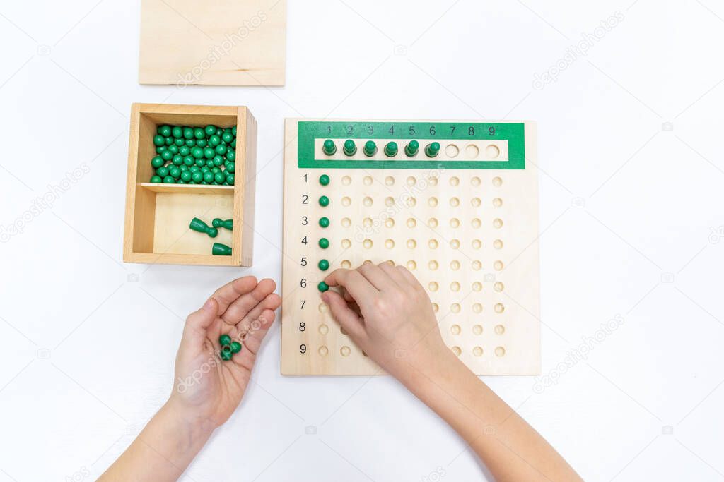 Top view of girls hand is playing and sorting a puzzle of colored plastic beads in montessori school. Concept of using a mathematical geometry learning resources for children education.