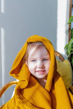 Defoktus. Küçük kız güneşin altında sallanan bir sandalyede oturur, kapalı alandaki bitkilerin arasında. Parlak gölge. Samimi insanlar konsepti. Evde dinlen.