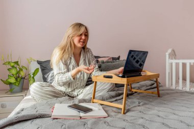 Defoktus. İnternette psikoterapi gören genç bir kadın yatak odasında yatarken bilgisayar kullanıyor. Kız dizüstü bilgisayara benziyor. Halkın refahı kavramı. Evde konfor bölgesi var..