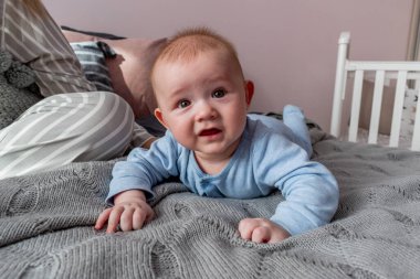 Bebek kameraya bakar ve genç annesinin yanında gülümser ve yatağa oturur. İyi sabahlar. Refah kavramı