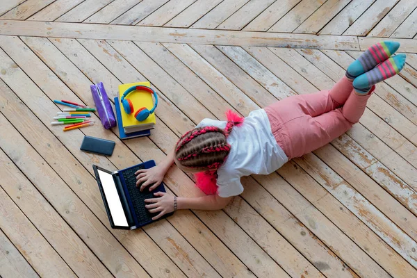 Girl work on laptop while lying on floor in room at home. Concept education is process teaching at school. Teenager studying the computer. Copy space