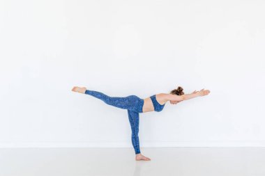 Yoga yapan genç, çekici bir Yogi kadını. Egzersiz kuşu köpek pozu. Stüdyo beyaz arka plan. Spor ve refah. Boşluğu kopyala