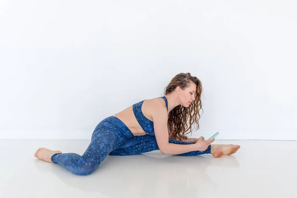 Wanita Muda Yang Beragam Menggunakan Ponsel Melakukan Yoga Duduk Lantai — Stok Foto