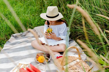 Dışarıdaki kız cam piknik kupasından limonata içiyor. Gençler boş zamanlarını geçirirler. Sağlık psikolojik sağlık konsepti. Taze meyve, çevre dostu.