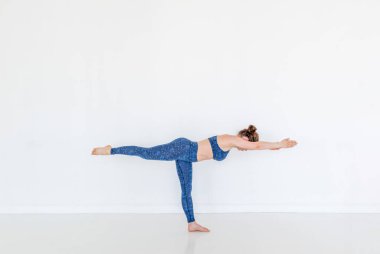 Yoga yapan genç, çekici bir Yogi kadını. Egzersiz kuşu köpek pozu. Stüdyo beyaz arka plan. Spor ve refah. Boşluğu kopyala