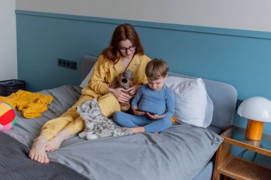 Genç anne ve oğlu çizgi film izliyorlar. Cep telefonu. Psikolojik sağlık konsepti. Sabah yatakta. Yaşam tarzını yavaşlatıyor