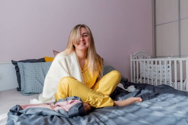 Genç kadın yatak odasında yatarken beyaz ekose kumaşa sarılmış. Sağlık ve akıl sağlığı konsepti. Sakin pastel renkler.