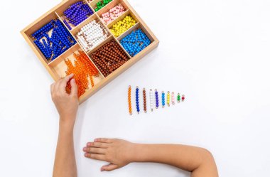 Kızların elinin en üst görüntüsü, Montessori okulunda renkli plastik boncuklarla oynamak ve sıralamak. Matematiksel geometri kullanma kavramı çocuk eğitimi için kaynak öğrenme kavramı.