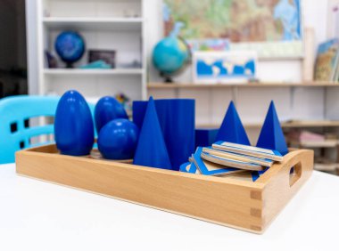 Montessori okulunda renkli ahşap geometrik şekillerle oynayıp, sıralamak. Matematiksel geometri kullanma kavramı çocuk eğitimi için kaynak öğrenme kavramı.