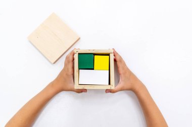 Kızların elinin en üst görüntüsü, Montessori okulundaki renkli ahşap geometrik şekiller bulmacasını çözmek ve oynamaktır. Matematiksel geometri kullanma kavramı çocuk eğitimi için kaynak öğrenme kavramı.