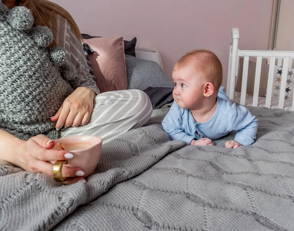 若い女性はベッドルームでベッドに座り 隣のコーヒーを飲むのは幼児です おはようございます ウェルネスコンセプト — ストック写真