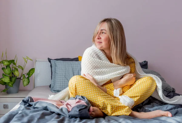 寝室でベッドに座りながら白衣に包まれる若い女 健康と精神衛生の概念 落ち着いたパステルカラー — ストック写真