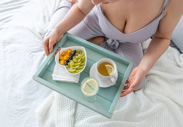 絹のパジャマの若い女性は寝室に寝そべっている間健康な朝食を有する 家庭の幸福の概念 若い女性の感情的な健康 — ストック写真