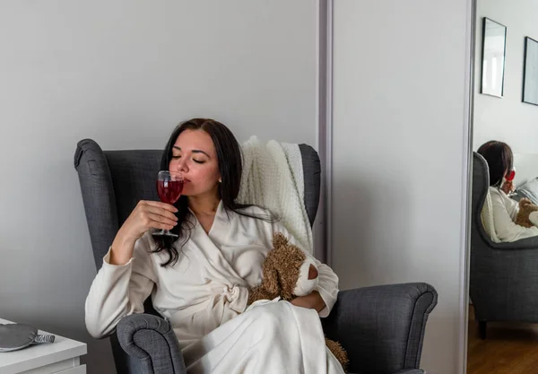 快適な白いローブの若い女性は 彼女の手にワインのガラスを保持しています リラックスと自分自身のための時間 新常態概念 — ストック写真