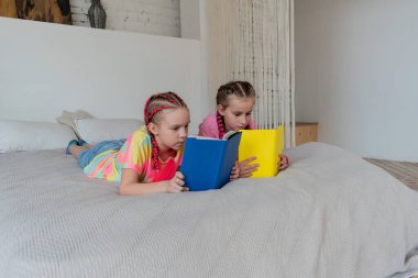 Kız arkadaşlar evde yatakta uzanmış kitap okurlar. Kavramsal eğitim okulda süreçtir. Gençler ders çalışıyor. Boşluğu kopyala