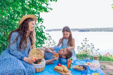 Aile pikniği. Anne ve çocuklar doğada öğle yemeği yiyorlar. Sağlık konsepti. İnsanlar için sağlıklı yiyecek..